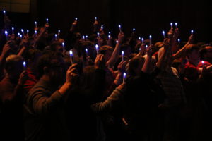 Students raise their blue candles in remembrance of Rumely, surrounding Rumleys family. 