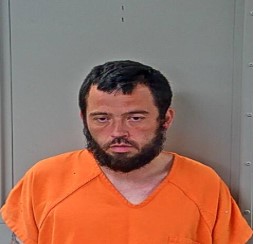 mug shot of arrested Dustin Hughes. Shorter white male, with a round face and short hair and beard. 