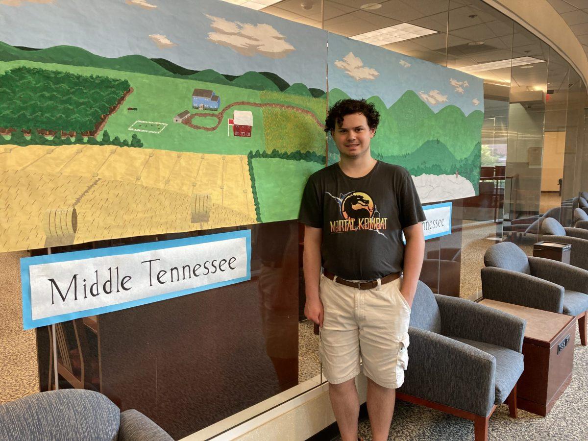 MTSU senior Will Breeding stands in front of his paper mural in the James E. Walker Library. (Photo by Luke Cameron)