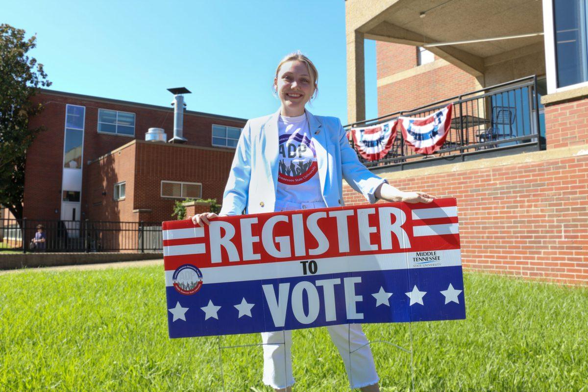 Club secretary for the American Democracy Project, Kayla Jenkins, is standing in front of the KUC urging people to register to vote.