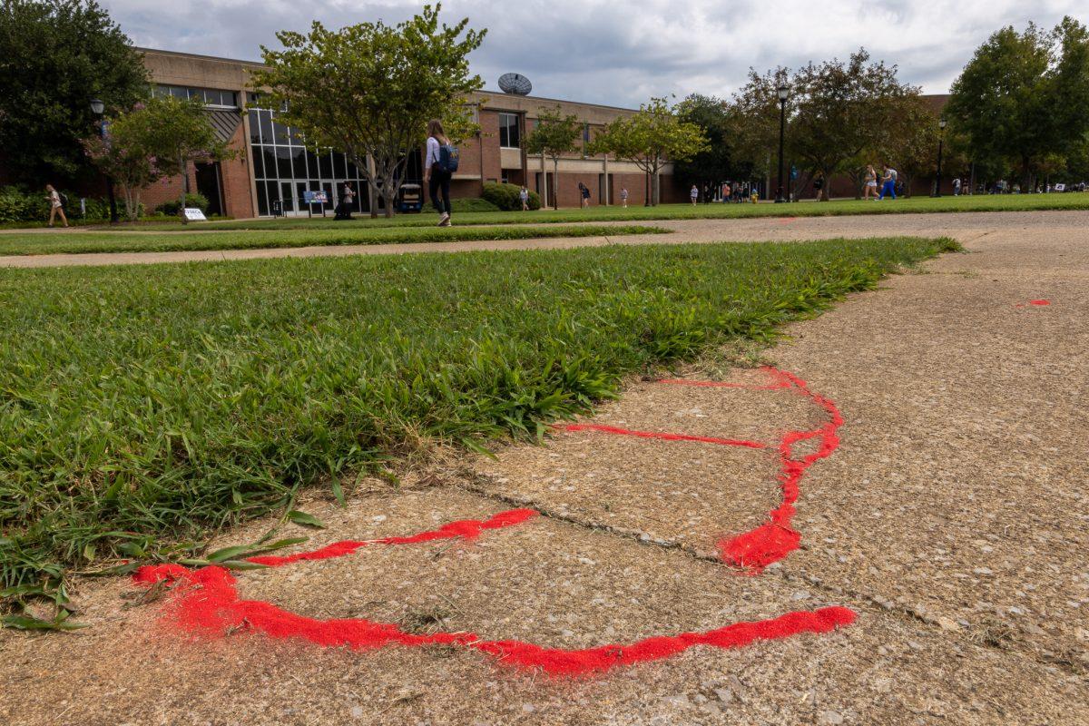 MTSU students poured red sand into sidewalk cracks on Sept. 2, 2022 as part of the Red Sand Project to signify the countless victims of human trafficking who regularly “fall through the cracks.” Staff from the Rutherford County Health Department hosted the event between the McWherter Learning Resource Center and the Science Building and educated students on the reality of modern human trafficking. (Photo by Bill Lickman)