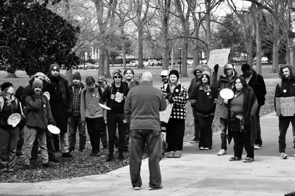 Marchers chant for biweekly pay as one student, Levi Dandridge holds up a sign that says “Biweekly Pay or I Freeze.” (Photo by Maia O'Brien)