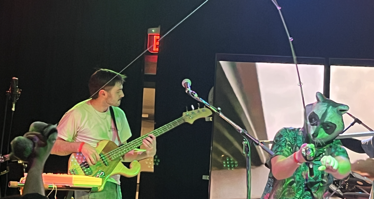 Jackson Buckner of Munkn performs beside a man in a raccoon mask, Feb. 22, 2025.