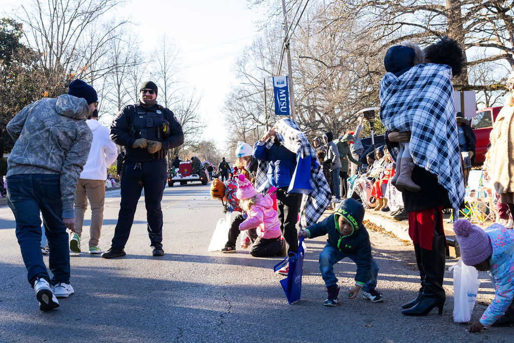 Micheal Cpaddock watches over kids as they gather candy during the Murfreesboro Christmas Parade on E Main St. on Dec. 14, 2025 