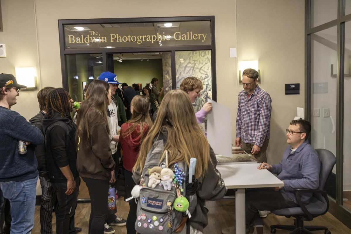 Ian Edward White signs posters for students at his Artist Talk at the John Bragg building on Feb. 26, 2026. 