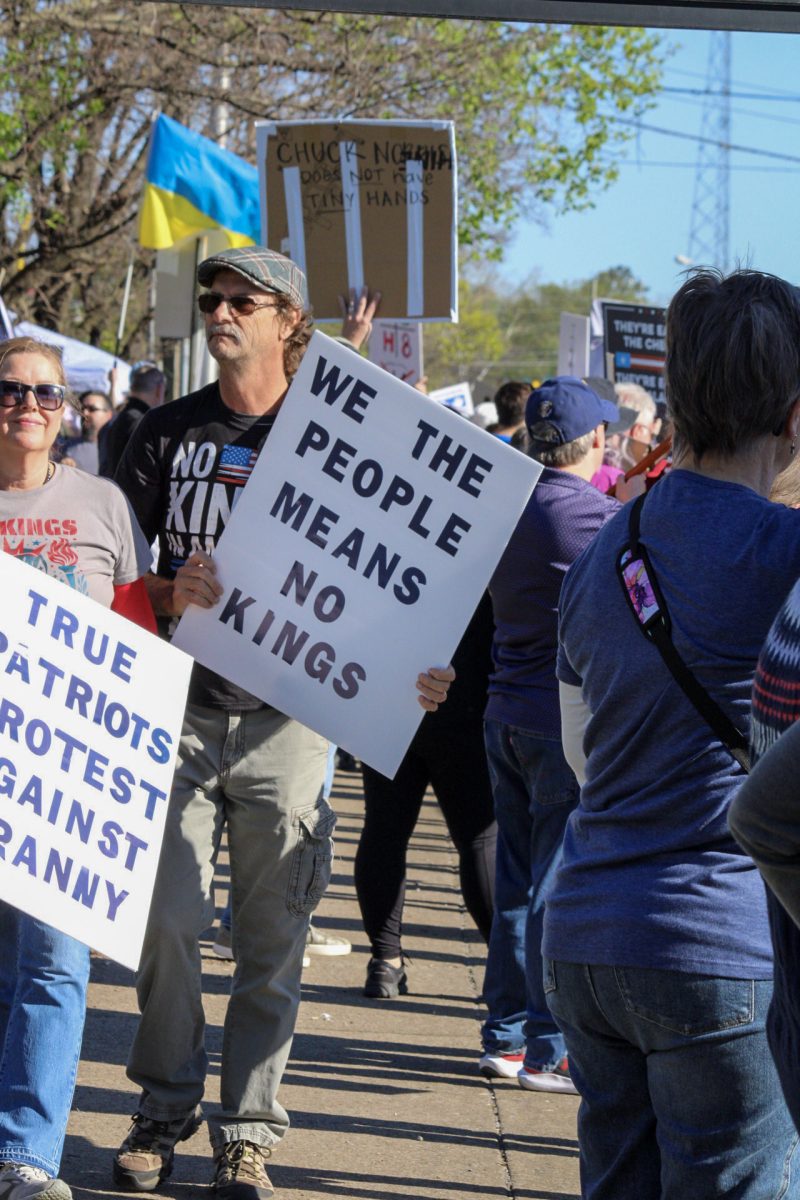 Protester walks along Broad Street holding a sign that reads ‘We the people means no kings’ at the "No Kings" protest in Murfreesboro, Tennessee, on March 28, 2026.