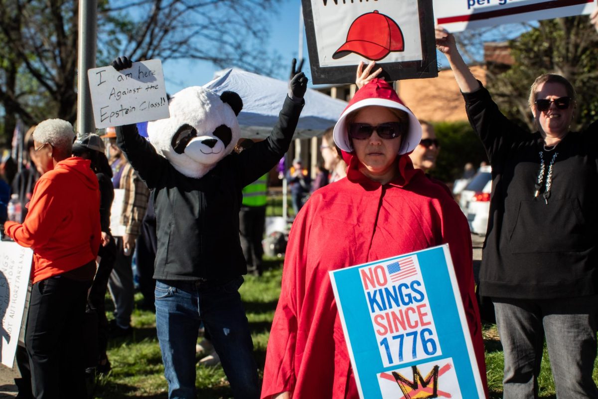 A protester dressed as a handmaid from "The Handmaid's Tale" holds a picket sign on Broad Street in Murfreesboro, Tennessee, on March 28, 2026.