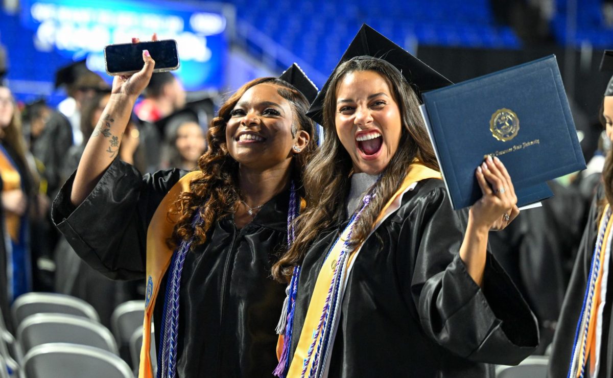 Two graduates pose while walking off the stage during spring commencement inside the Murphy Center on May 9, 2026.
