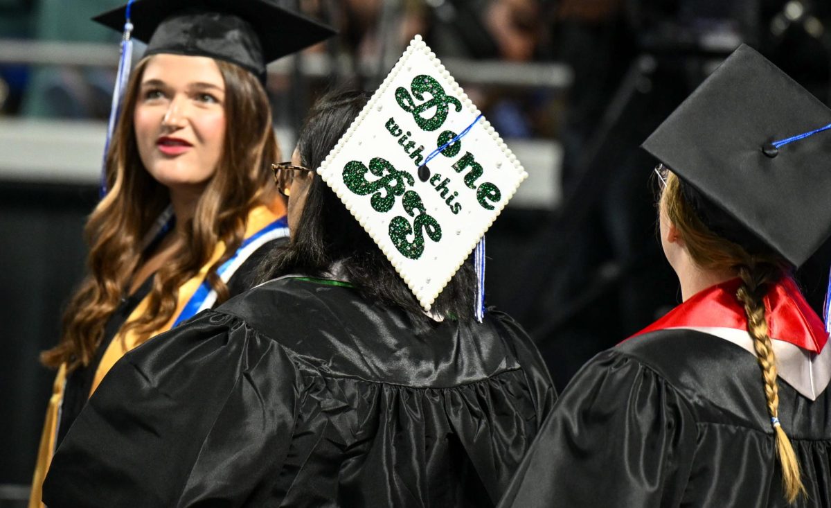 A graduate walks onto the floor with a mortarboard decorated with the phrase "Done with this BS" during spring commencement inside the Murphy Center on May 9, 2026.