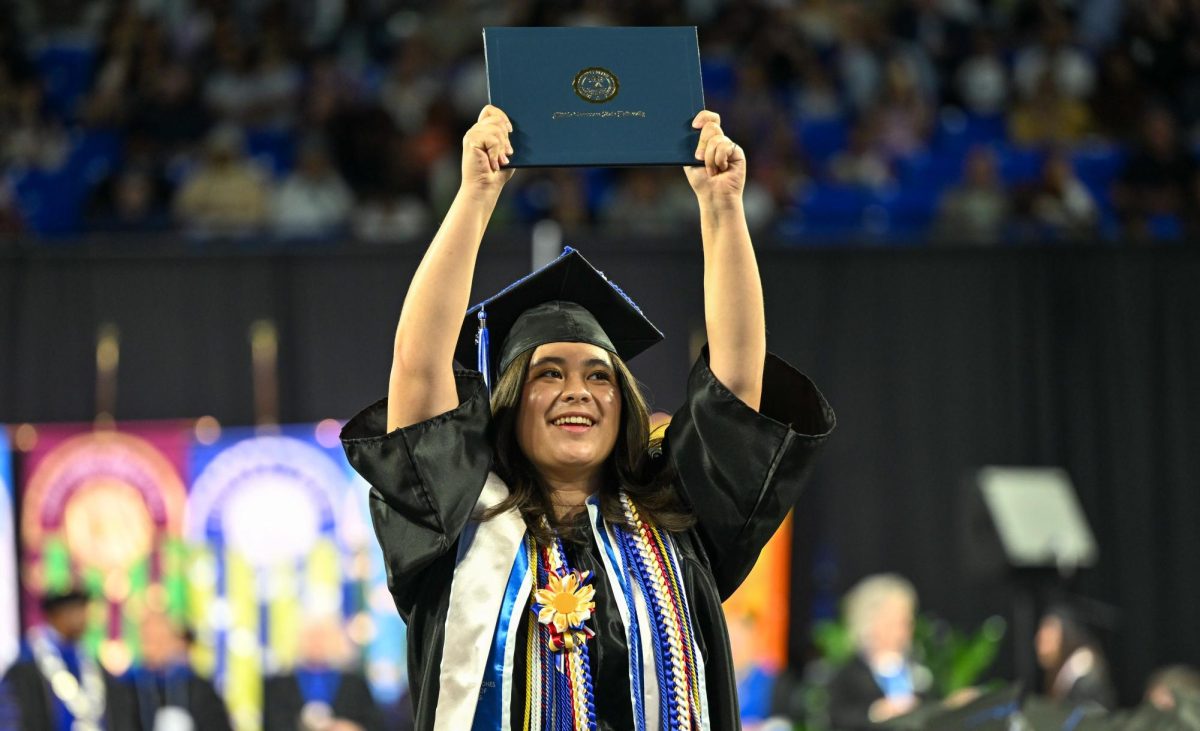 MTSU graduate Samantha Jones holds up her diploma after walking across the stage during spring commencement inside the Murphy Center on May 9, 2026.