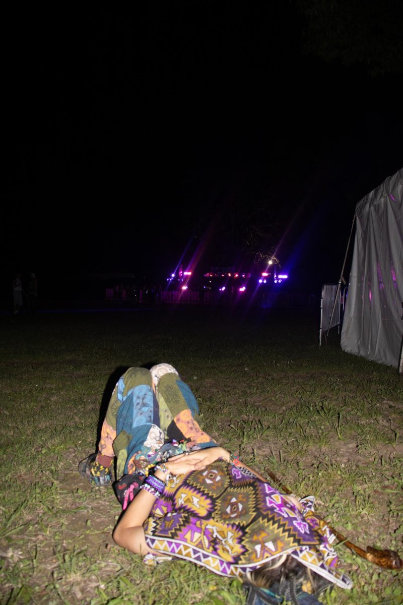 In between This Tent and Which Stage, a fan lies down in the grass listening to the live music at Bonnaroo Music & Arts Festival, 2026.