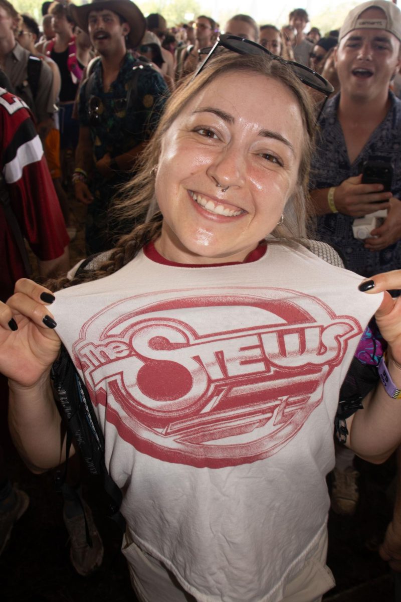 Fan holds up The Stews t-shirt in the That Tent pit at Bonnaroo Music & Arts Festival, 2026.