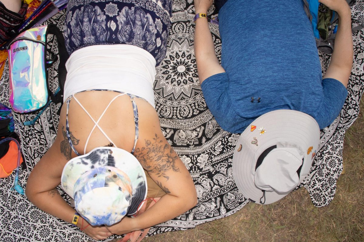 Two fans relax on the grass near the Which Stage at Bonnaroo Music & Arts Festival, 2026. 